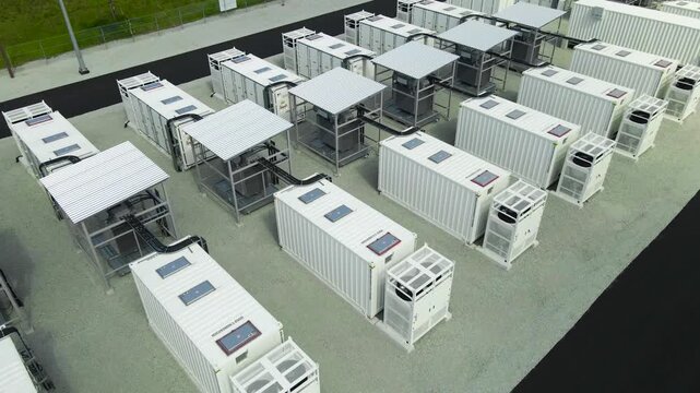 Aerial perspective revealing a modern battery energy storage system park with containerized units, cooling systems, and an adjacent electrical substation, showcasing renewable energy infrastructure