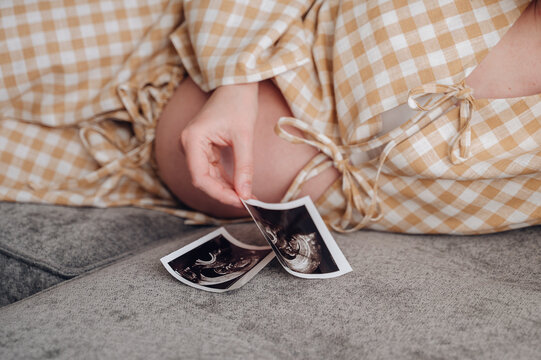 Pregnant woman relaxing on sofa holding ultrasound print