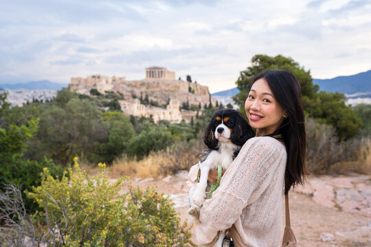 Tourist holding small dog with Acropolis view in Athens