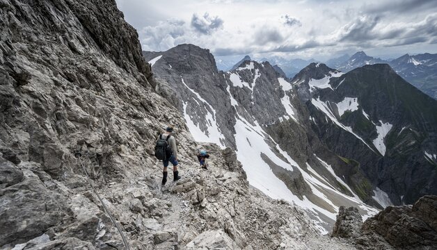 Hiker and woman descending rocky terrain, mountain panorama with rocky peaks in the background, dramatic cloudy sky, Heilbronner Weg, Allg&auml;u Alps, Allg&auml;u, Bavaria, Germany