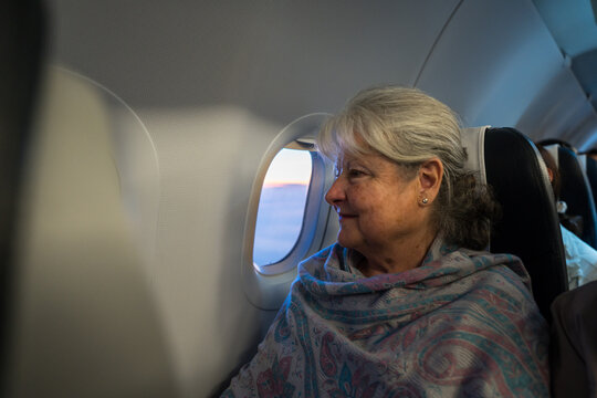 Senior woman enjoying sunset view from airplane window seat