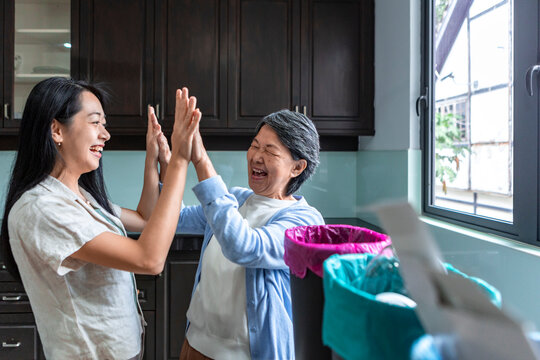Asian mother and grandmother high five after recycling at home