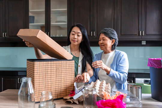 Asian family sorting recyclables at home kitchen table