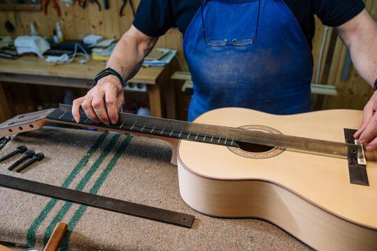 Skilled retiree crafting guitar in Spanish workshop