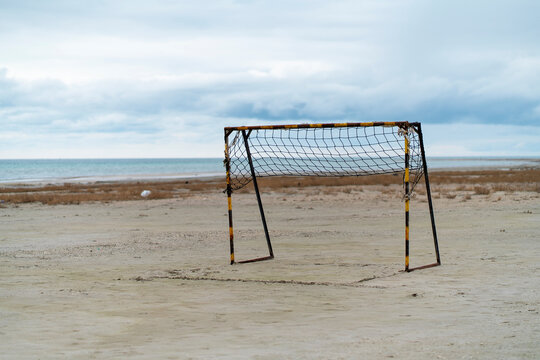 Abandoned soccer goal on empty beach under cloudy sky