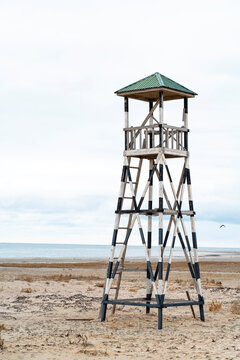 Wooden lifeguard tower on empty beach under cloudy sky