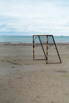 Abandoned soccer goal on empty beach under cloudy sky