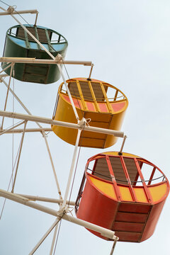 Colorful observation wheel gondola against pale sky