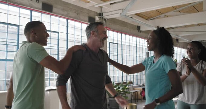 Diverse peers clapping and highfiving after mid-40s man lifting barbell in gray top in loft