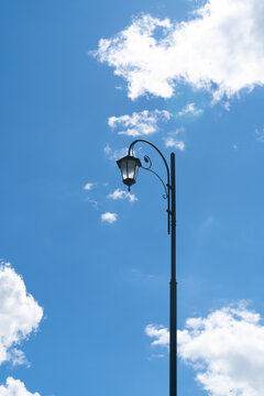 Vintage street lamp against bright blue sky with cloud