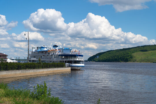River cruise ship docked by embankment under clouds