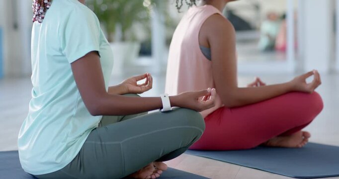 African women meditating for calm on mats in studio, in mudra while camera widening showing mirror