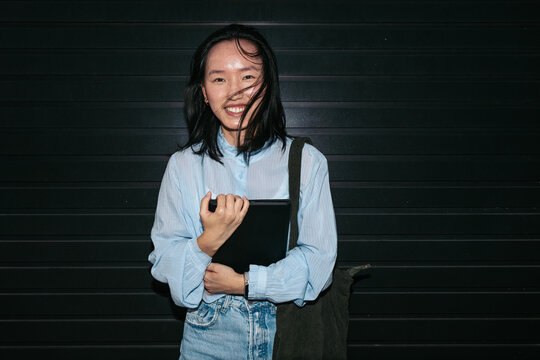 Smiling businesswoman holding a tablet outside