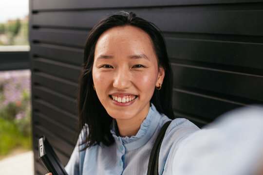 Smiling businesswoman taking a phone selfie outdoors