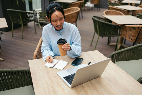 Businesswoman working outdoors with coffee and laptop