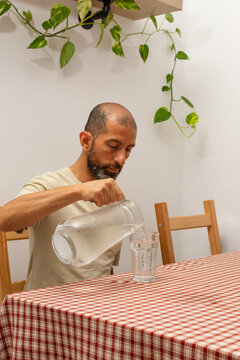 Hispanic man serving cold drinking water at home during extreme summer heat