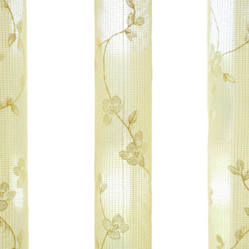 Translucent sheer curtains in primrose yellow with delicate floral patterns hanging in front of a sunlit window, fabric texture in a bright breezy morning atmosphere