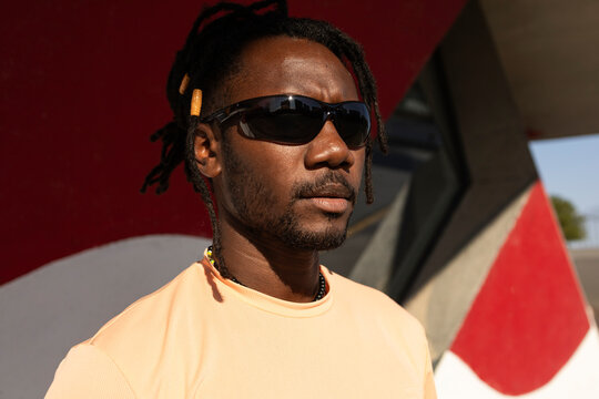 Cuban man in sunglasses with dreadlock hair outdoors