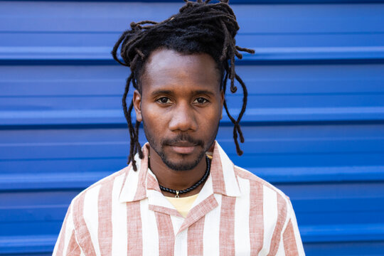 Cuban man portrait with dreadlocks against blue wall