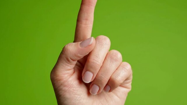 Hand gesturing number one or warning sign isolated on green screen chroma key background, gesture finger