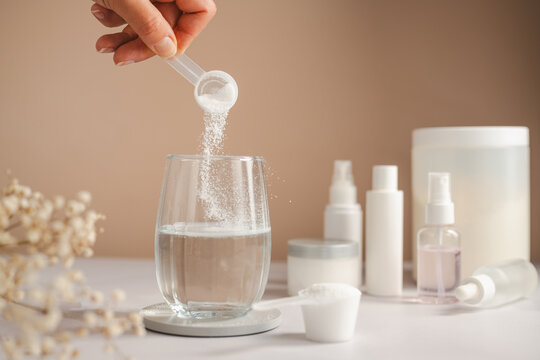 Woman adding collagen supplement to water alongside skincare products and self care routine