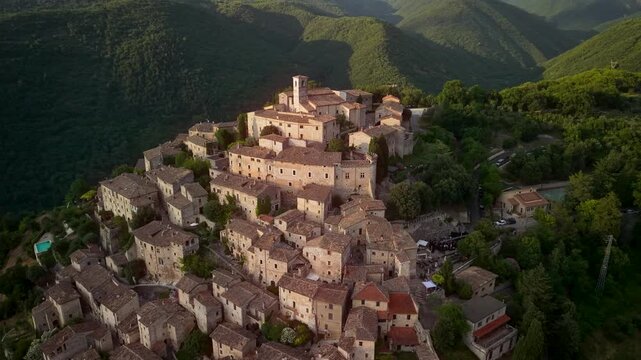 Labro Rieti Italy 70mm drone sunset pullaway view of authentic medieval hilltop borgo. Cinematic 4k rotation reveal panorama of pyramid stone village among green hills landscape b-roll video
