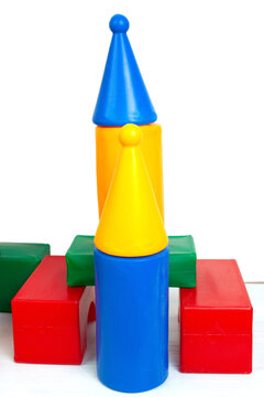 A colorful rocket built from plastic toy blocks standing on a white surface.