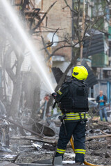 Fototapeta premium Brave firefighter battling a blaze amidst debris and a burnt car wreckage