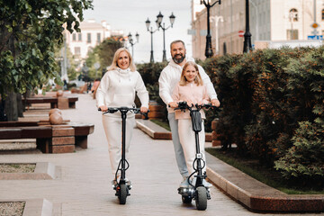 Fototapeta premium A family in white clothes rides electric scooters in the city.Outdoor activities
