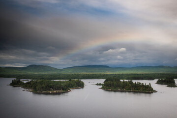 Obraz premium Rainbow over forested islands and lake