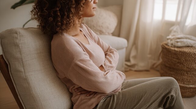 Pregnant person seated for coccyx pain relief with back support in a cozy home setting