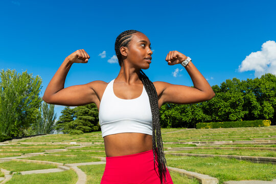 Gen Z Black woman flexing outdoors for fitness wellness