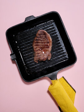 Grilled beef steak on a pan with pink background