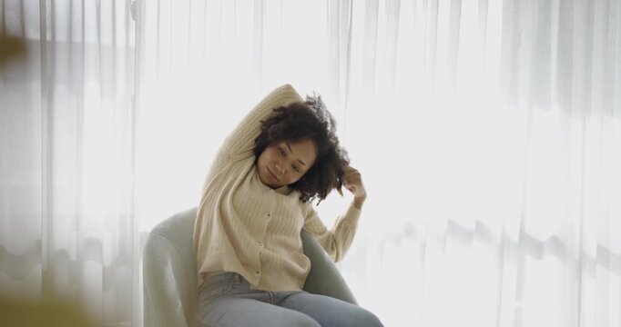 Young woman stretching sitting in chair near bright window, morning routine, self-care, and a healthy lifestyle. Wellness yoga winter time.