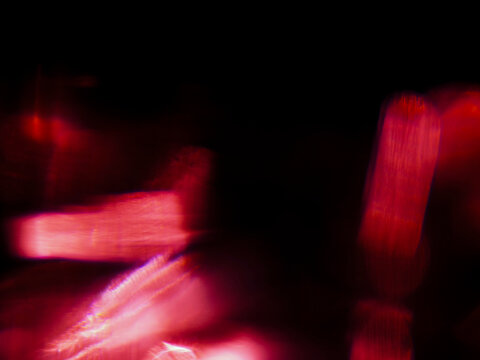 Abstract red light leaks with glowing red light streaks against dark background. Visual effect created by camera movement or light trails. Graphic background for design.
