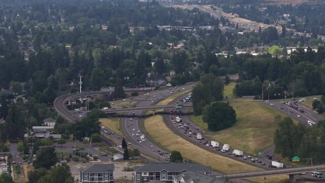 Aerial of Highway 205 and suburban development near Happy Valley Oregon with multilane freeways overpasses and forested hillsides in summer