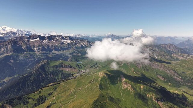 Survol a&eacute;rien des vertes vall&eacute;es alpines parsem&eacute;es de nuages en &eacute;t&eacute;
