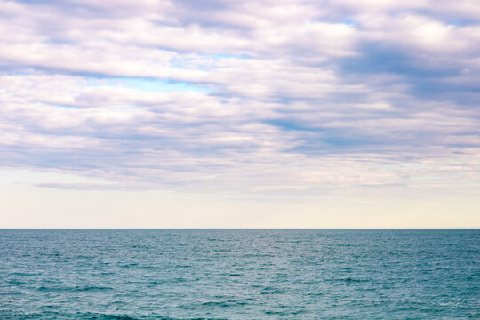 Tranquil seaside horizon under soft clouded sky