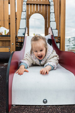 Young girl sliding down playground slide joyfully