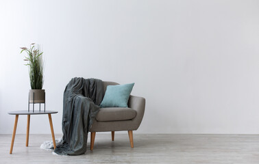 Modern boho cozy corner of home in living room. Gray vintage armchair with blue pillow and blanket,...