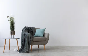 Fototapeten Restaurant Modern boho cozy corner of home in living room. Gray vintage armchair with blue pillow and blanket, table with green plant in pot, wooden floor, on light wall background, copy space, mockup, nobody  © Prostock-studio