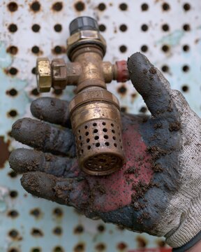 Dirty Gloved Hand Holding Brass Sprinkler Nozzle for Irrigation