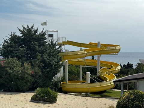 Bright yellow waterslide in a resort aquapark overlooking the sea