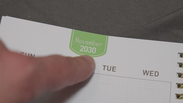 finger pointing at November 2030 planner page close up for scheduling and monthly planning concept