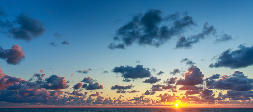 Incredible sunset over a wide ocean beach, on the background of a colourful, cloudy sky