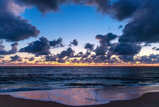 Incredible sunset over a wide ocean beach, on the background of a colourful, cloudy sky
