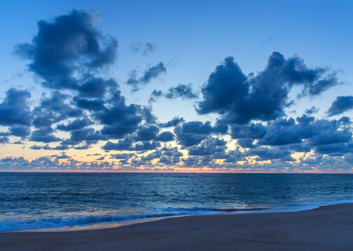 Incredible sunset over a wide ocean beach, on the background of a colourful, cloudy sky
