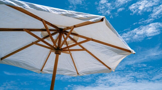 Umbrella's white underside shields from sun under blue sky, offering cool shade for outdoor summer trips and travel.