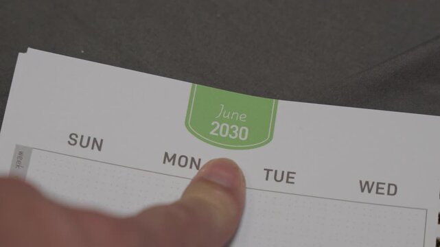 finger pointing at June 2030 planner page close up for scheduling and monthly planning concept