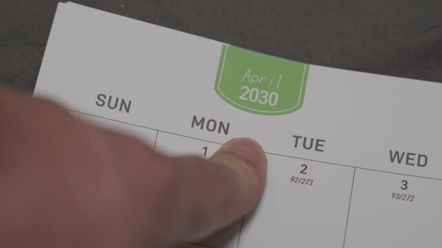 finger pointing at April 2030 planner page close up for scheduling and monthly planning concept